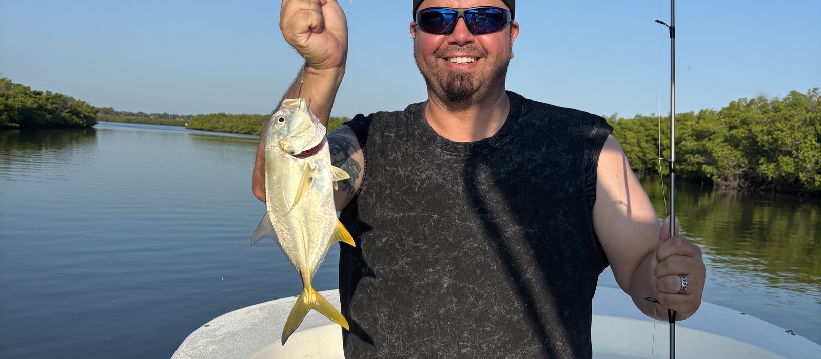 Angler fighting a hooked redfish on a New Smyrna Beach inshore fishing charter, Mosquito Lagoon flats in the background